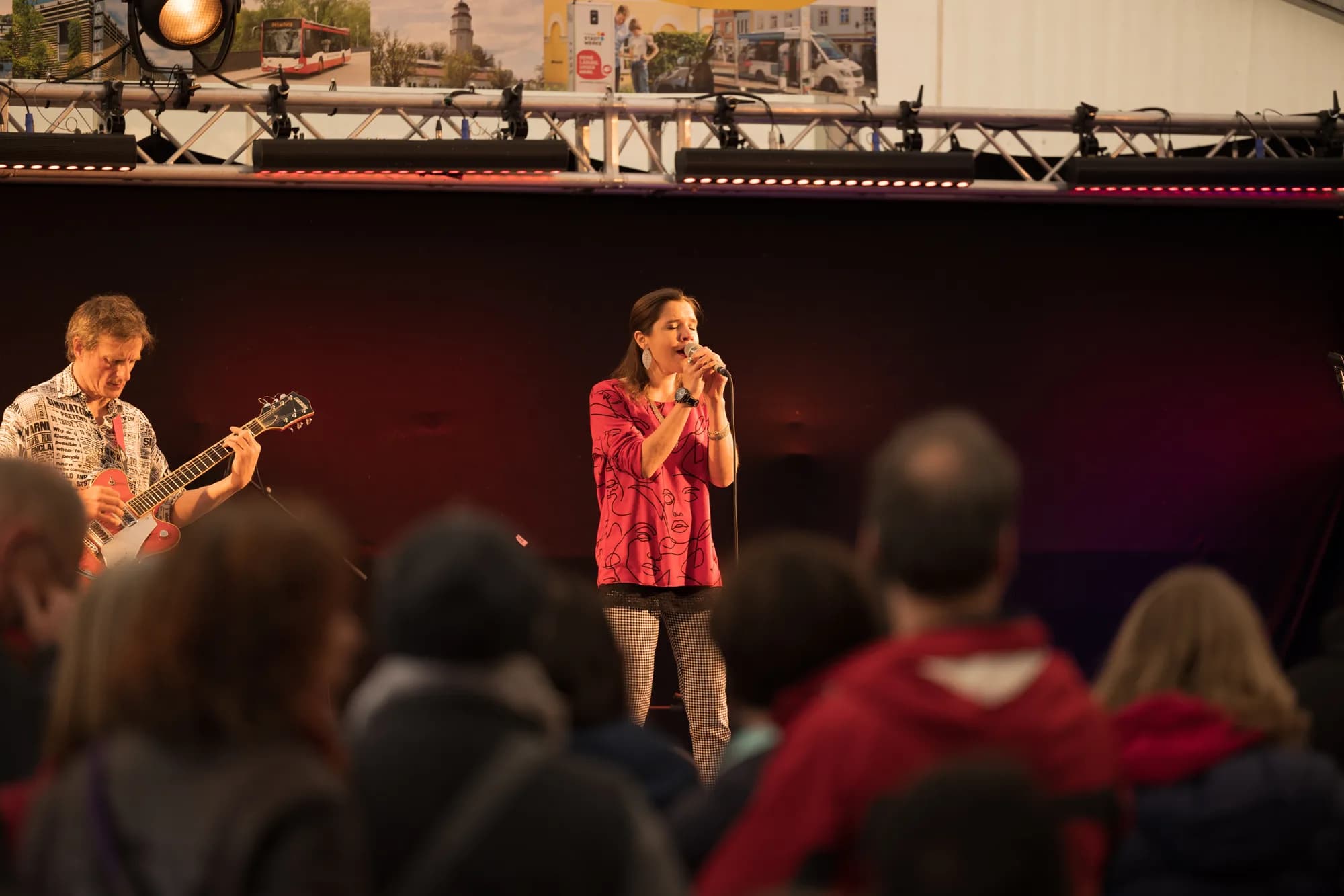 A female singer in a pink top performs with a guitarist on stage at the Uferlos festival.