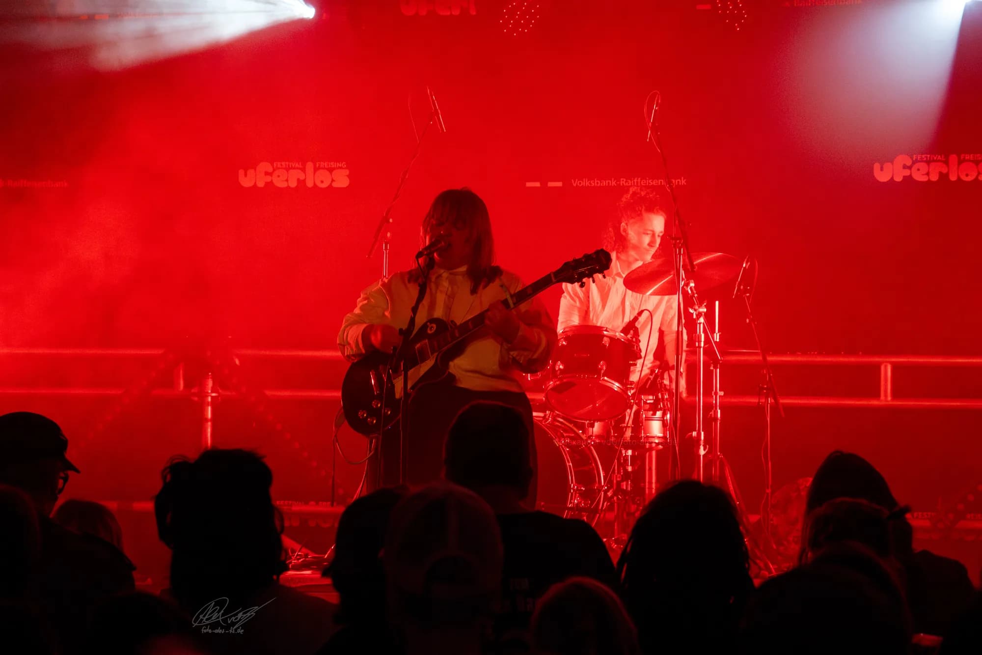 A vendor at the festival merchandise booth surrounded by colorful festival gear.
